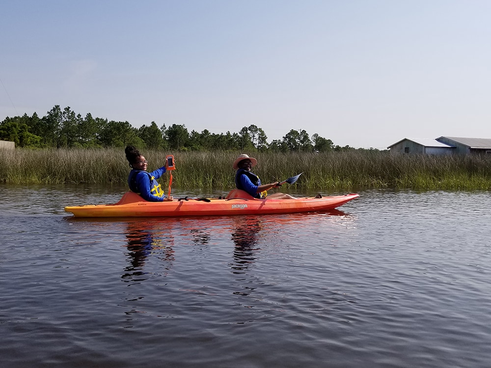 Two students kayaking and looking at the camera